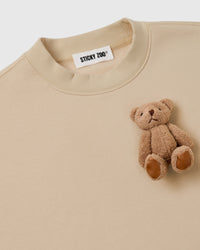 Close-up of single plush teddy bear on cream fleece showing embroidered features