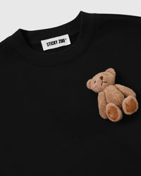 Close-up of single hand-stitched plush teddy bear on black 450gsm cotton fleece showing ribbed collar