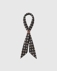 Obsidian silk coin scarf knotted through a leather slide showing the gold and cream medallions