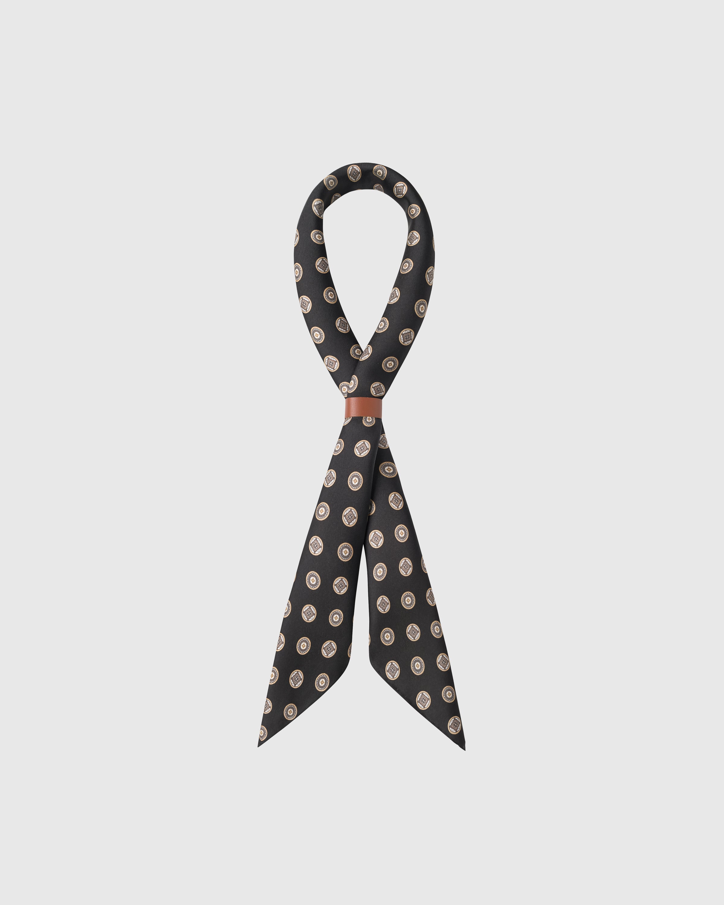 Obsidian silk coin scarf knotted through a leather slide showing the gold and cream medallions