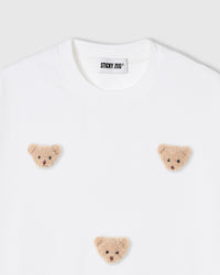 Close-up of plush bear face appliques on white 230gsm cotton showing fuzzy 3D texture and embroidered features