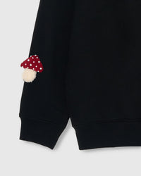 Close-up of hand-stitched mushroom on sleeve cuff showing stuffed dimensional texture