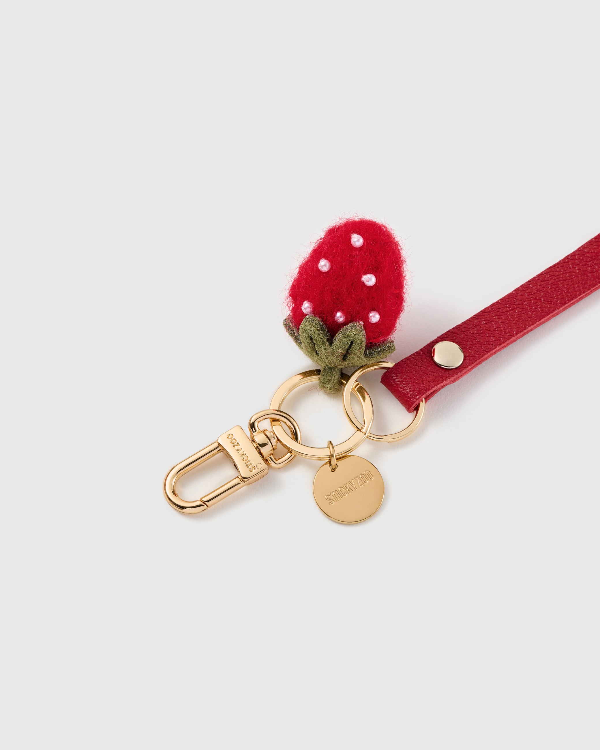 Wild strawberry leather phone strap clipped to a phone case showing the hands-free wrist loop in use