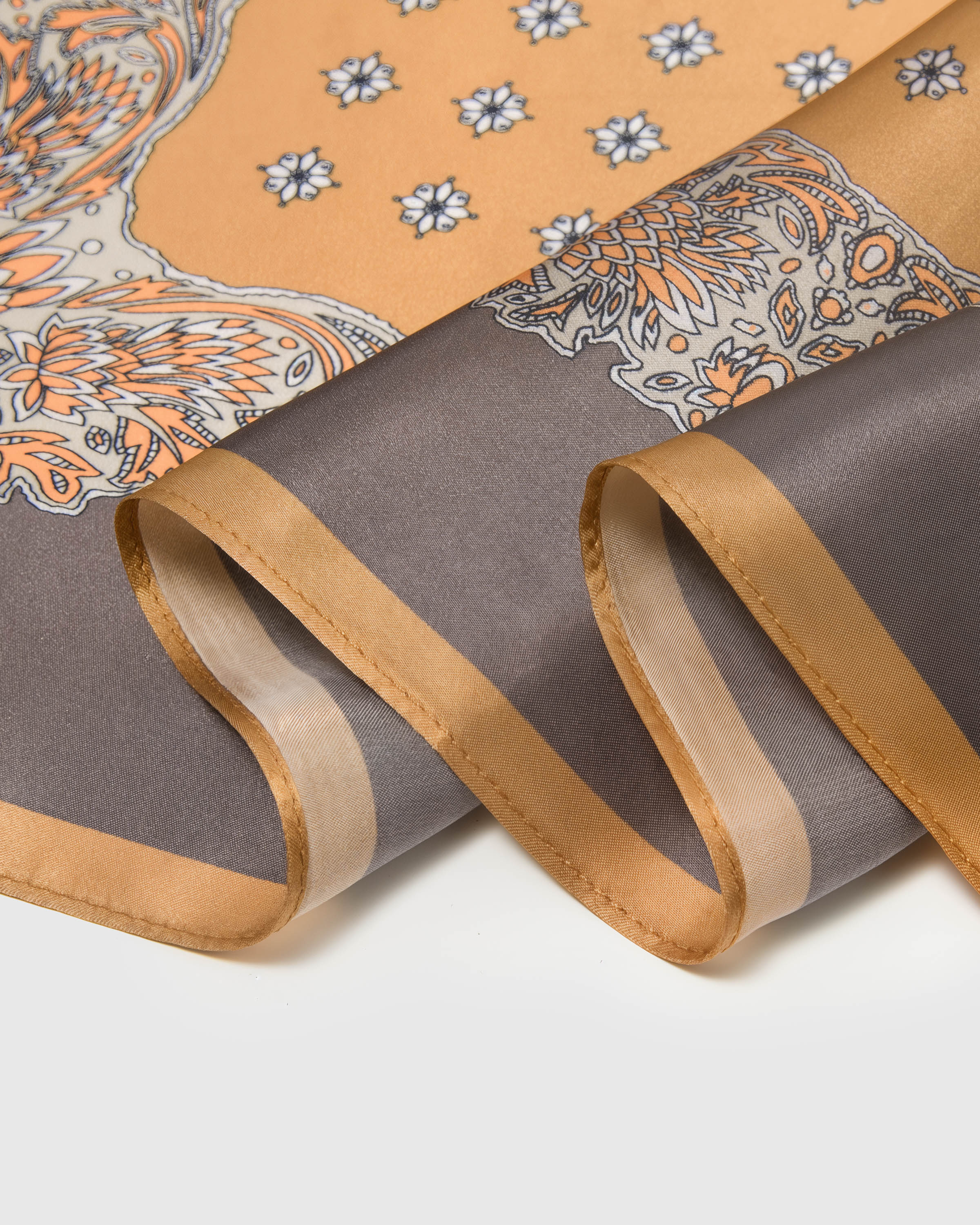 Close-up of the amber outer band and taupe paisley border meeting the print on pure silk
