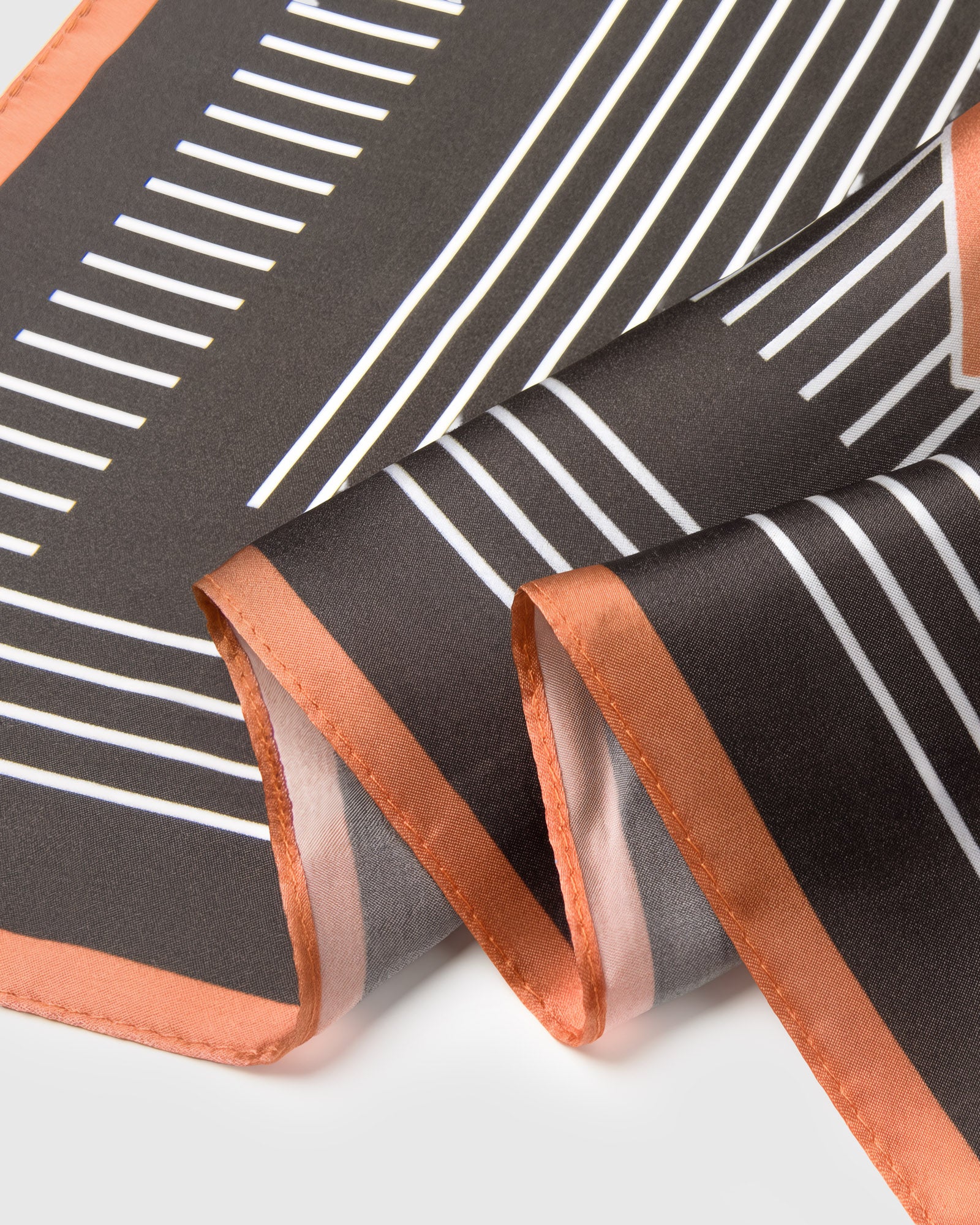 STICKYZOO op-art silk scarf folded into a triangular drape showing the concentric stripe geometry