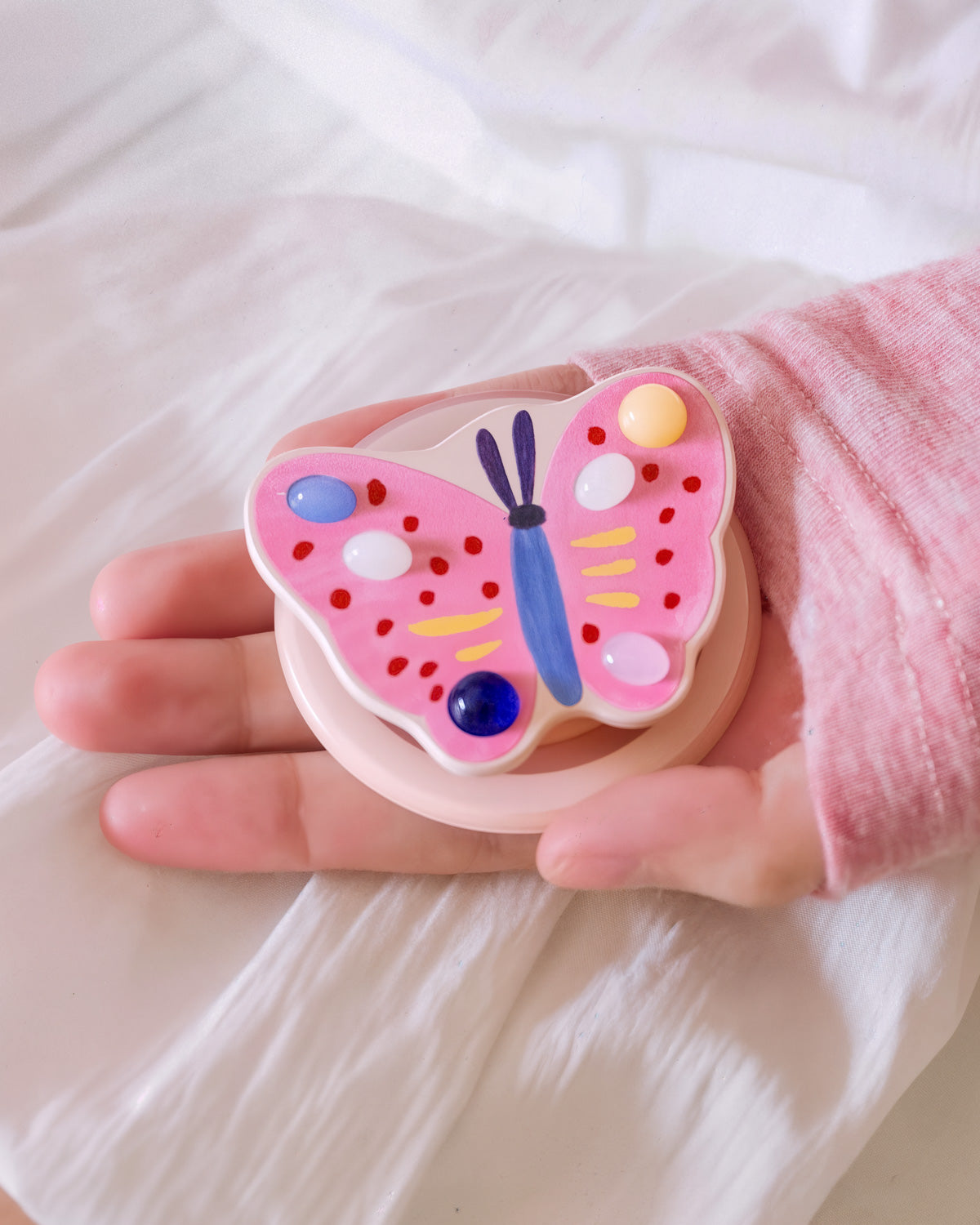 Close-up of the 3D pink butterfly medallion embedded inside the acrylic-resin pop-grip