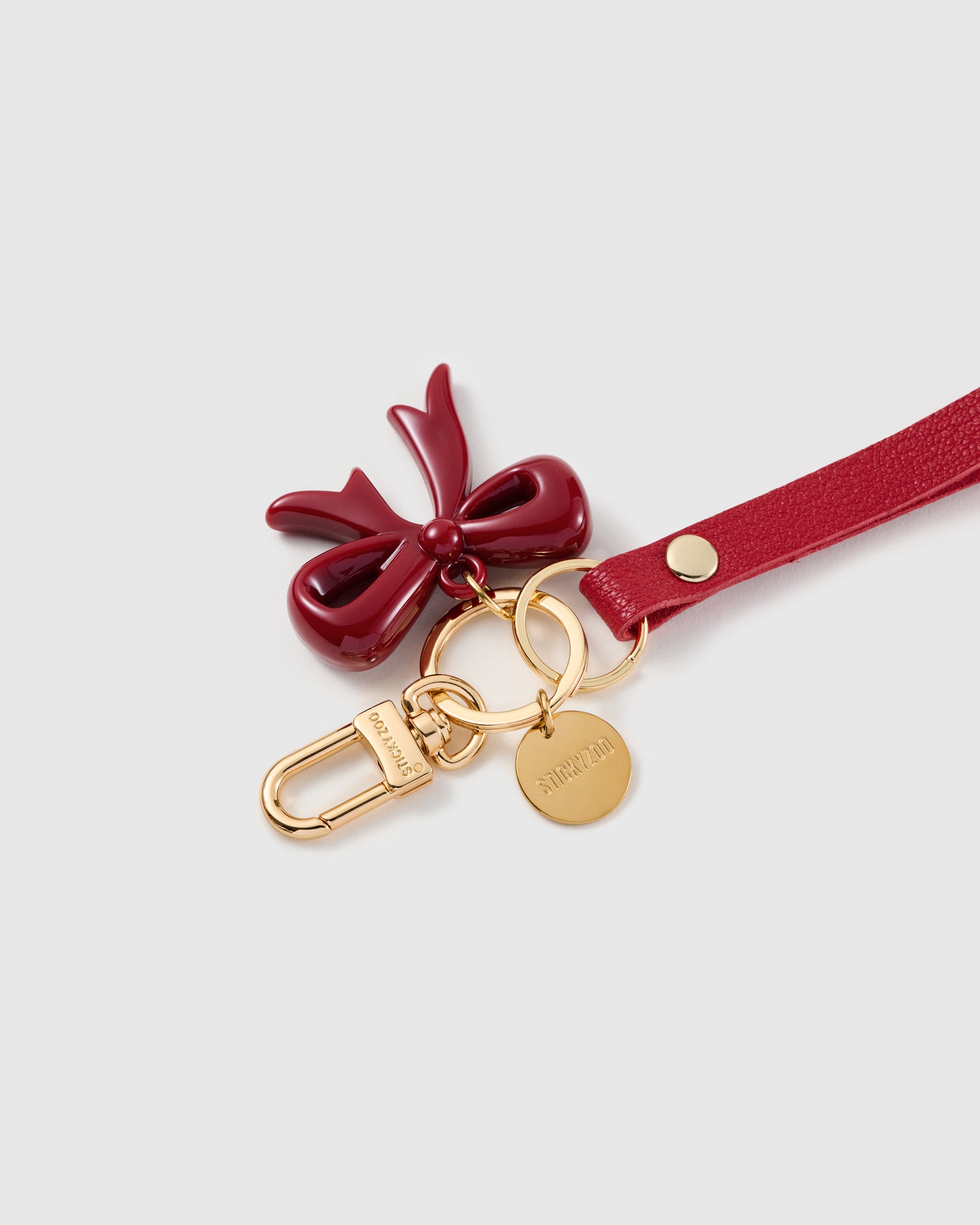Ruby bow leather phone strap clipped to a phone case showing the hands-free wrist loop in use