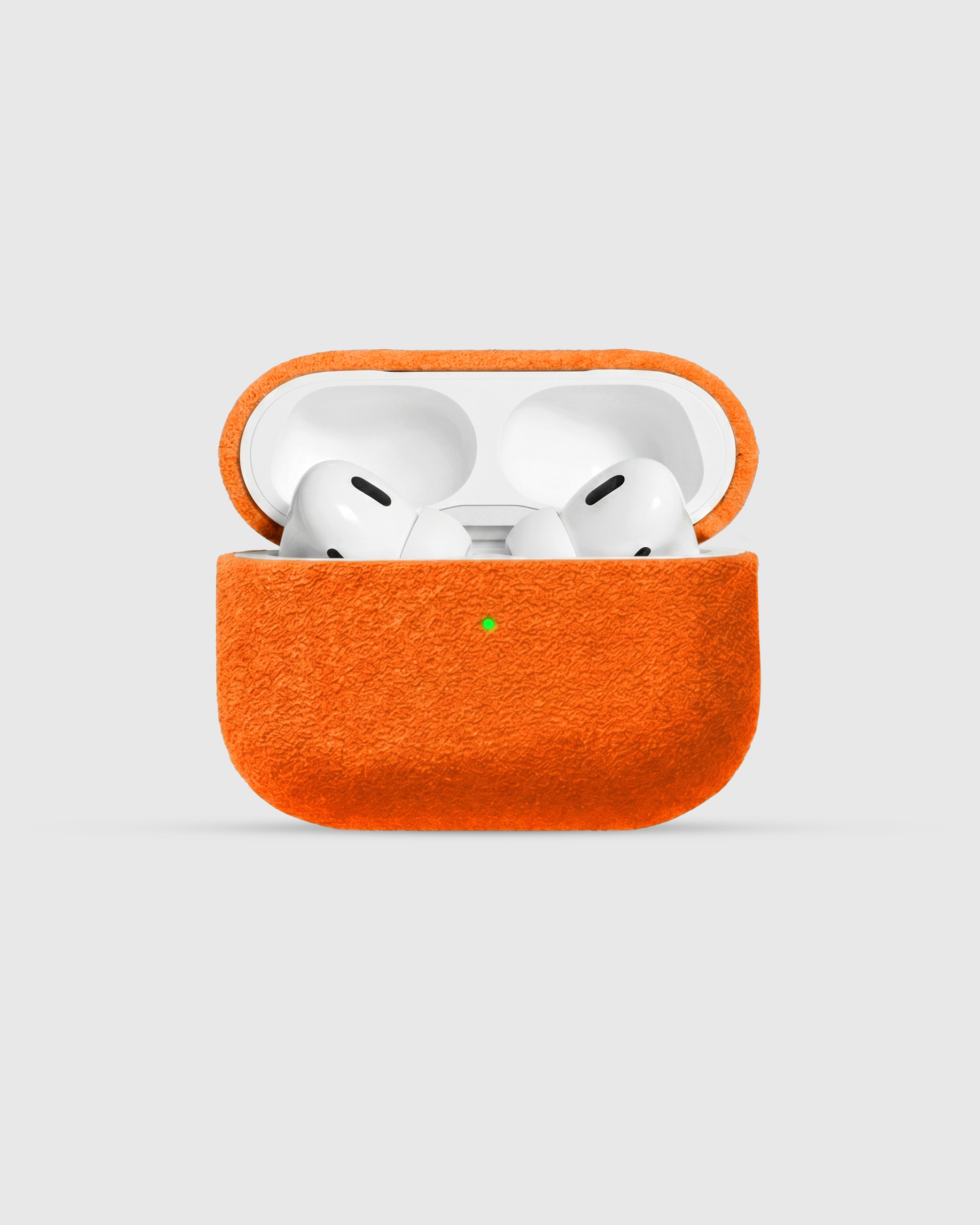 {{AirPods Pro fit securely.}} Tangerine Alcantara case open with AirPods Pro seated inside
