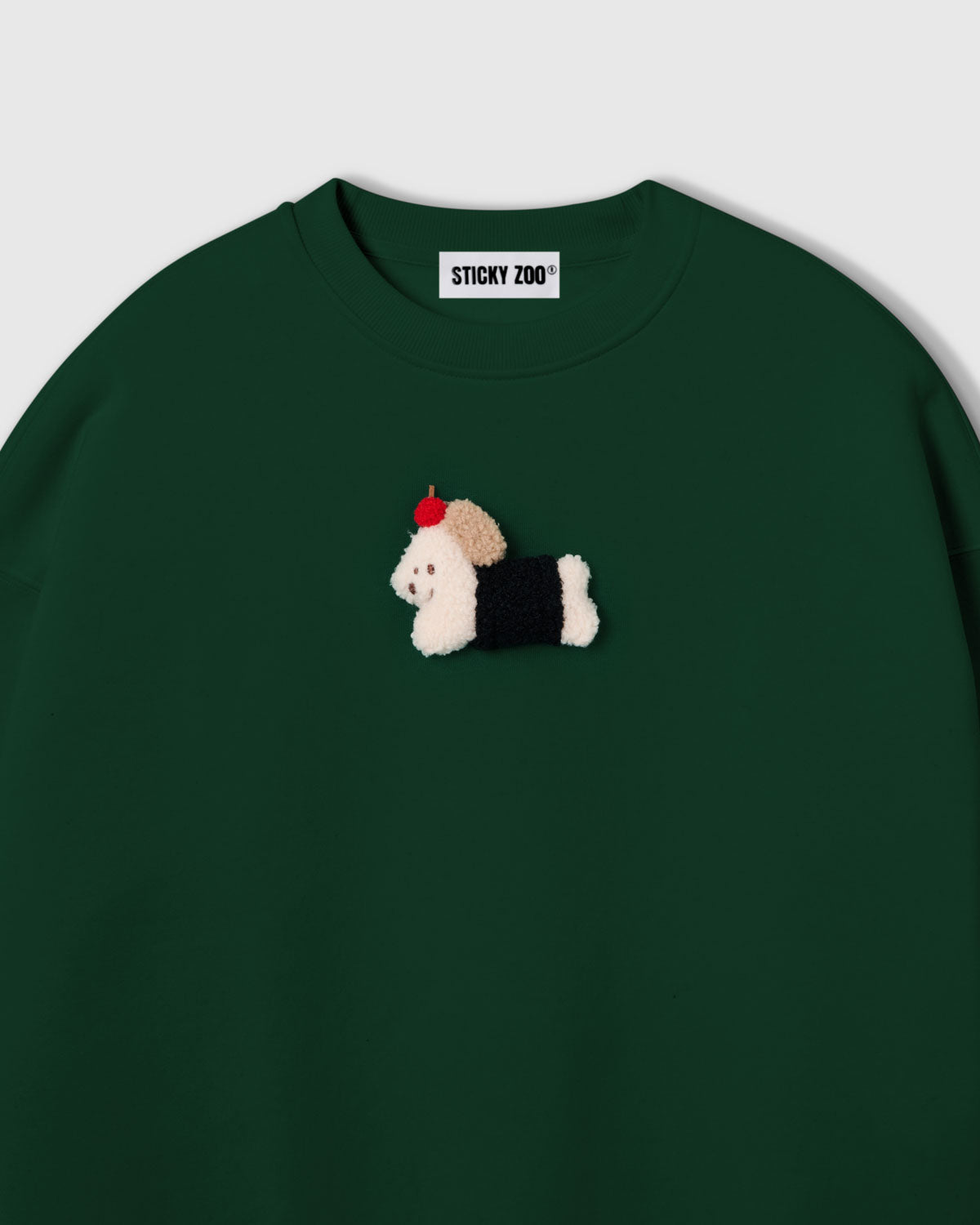 {{Not printed — stitched}} Close-up of plush dachshund in black coat with red apple on forest green cotton showing layered 3D texture