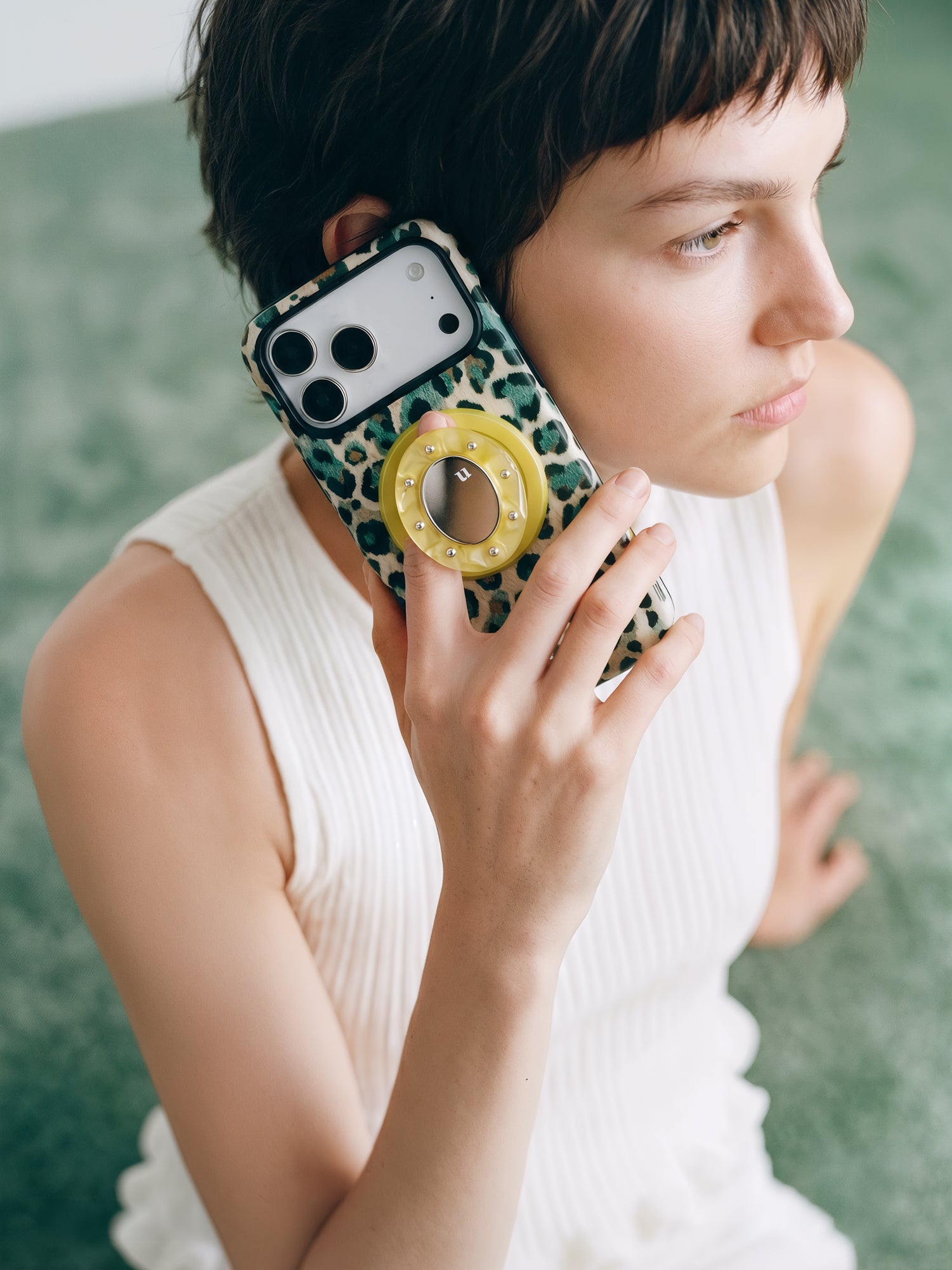 Jade leopard phone case held to the ear with the pop-grip extended for an easy one-handed hold.