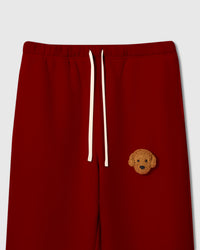 Close-up of hand-stitched plush poodle face on red 350gsm cotton sweatpant showing curly texture detail
