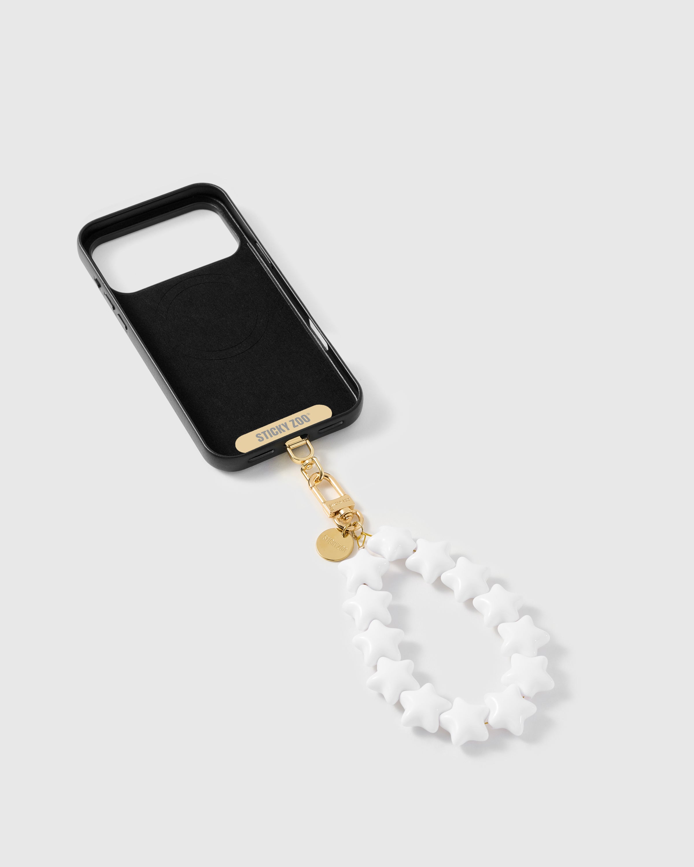 Inside of black phone case showing the STICKYZOO Phone Strap Card and gold-plated hardware connection