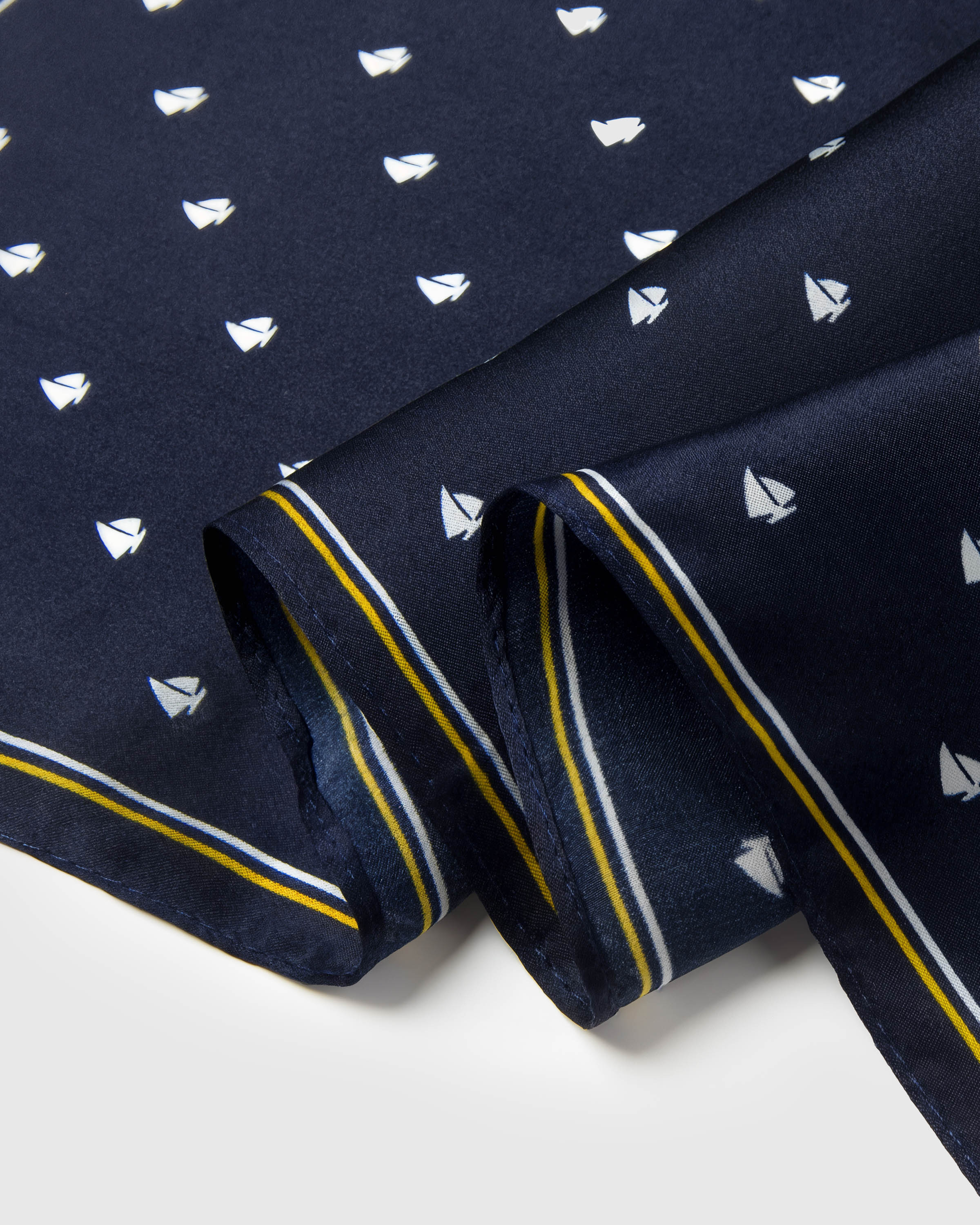 Close-up of the navy silk edge showing the mustard yellow stripe and small sailboat motif printed in archival ink