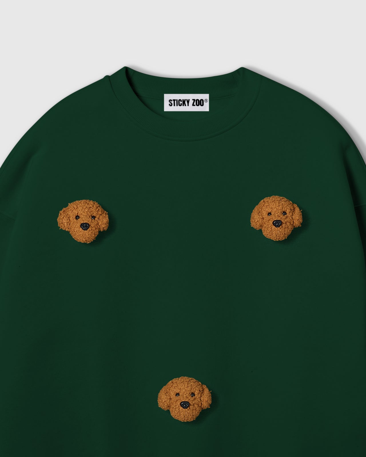 {{Not printed — stitched}} Close-up of plush poodle face on forest green cotton showing golden curly texture and embroidered detail