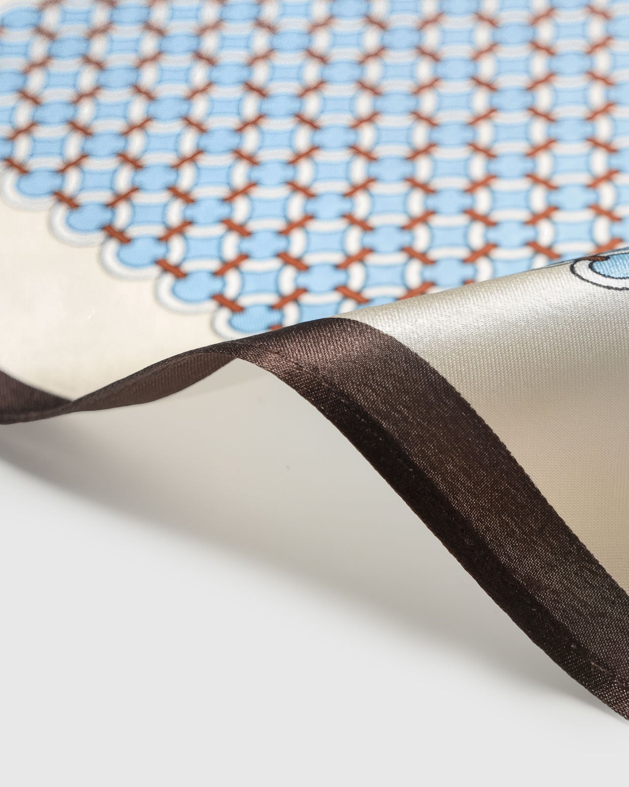 STICKYZOO blue trellis silk scarf coiled to reveal the geometric circle print and cognac stitches
```