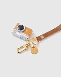 Tangerine lens leather phone strap clipped to a phone case showing the hands-free wrist loop in use