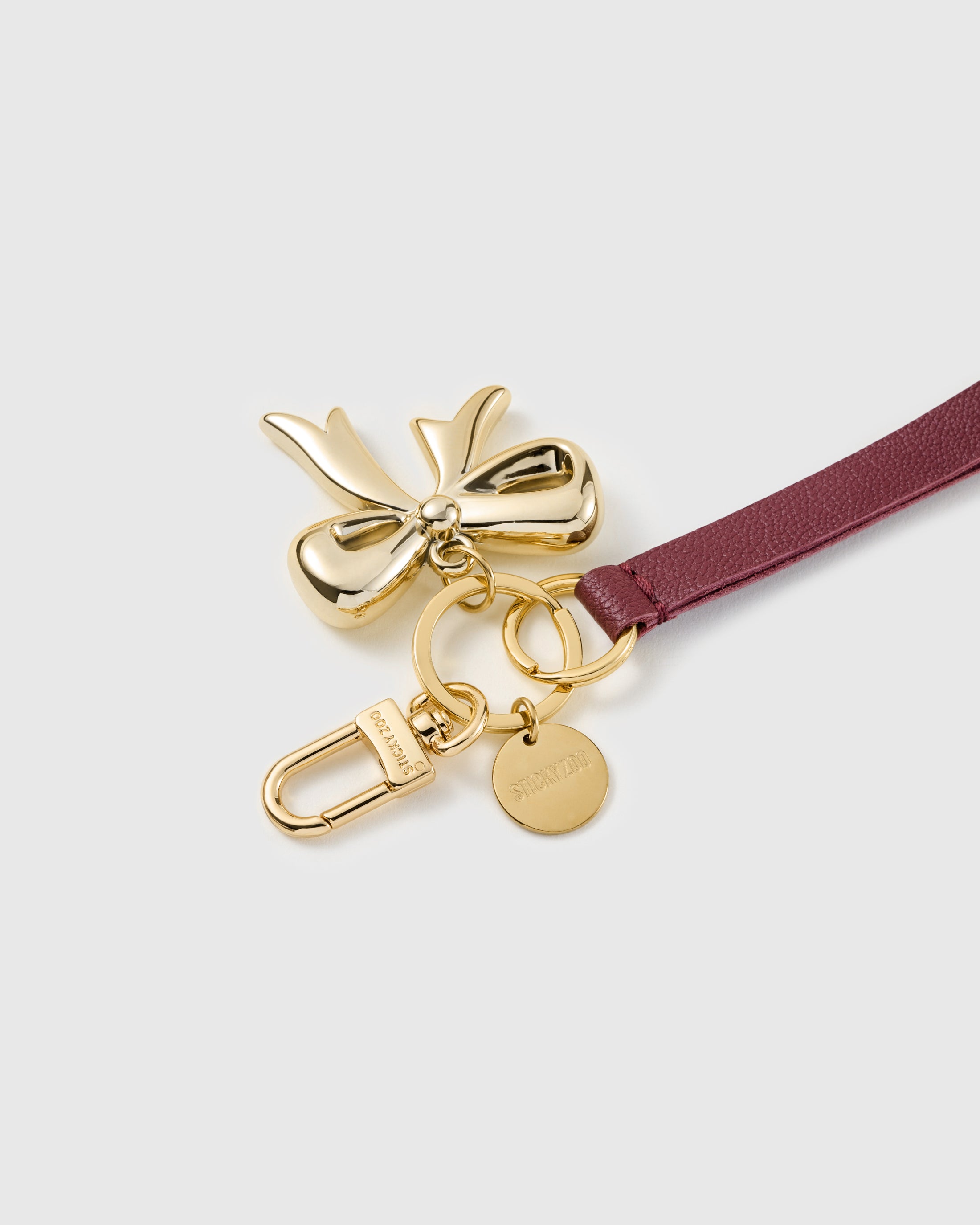 Golden bow leather phone strap clipped to a phone case showing the hands-free wrist loop in use