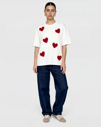 Detail of multiple plush heart appliques scattered across white cotton showing varied placement