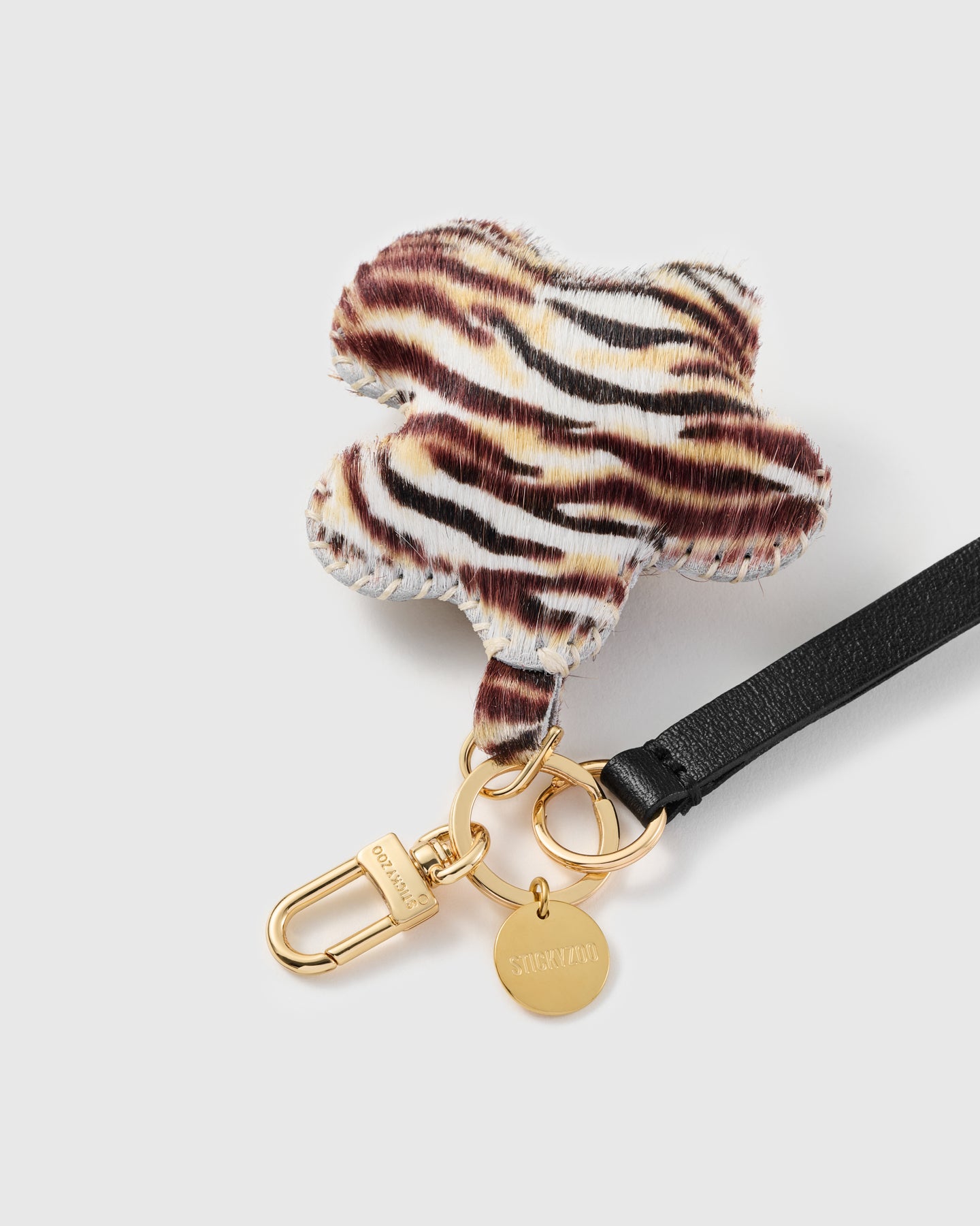 Tiger flower leather phone strap close-up — calf-hair charm, hand whip-stitched edge, STICKYZOO engraved hook