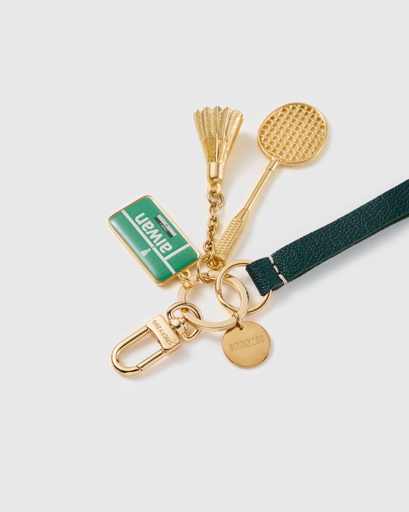 Close-up of three-charm cluster showing hand-set Taiwan enamel badge with gold racquet and shuttlecock detail