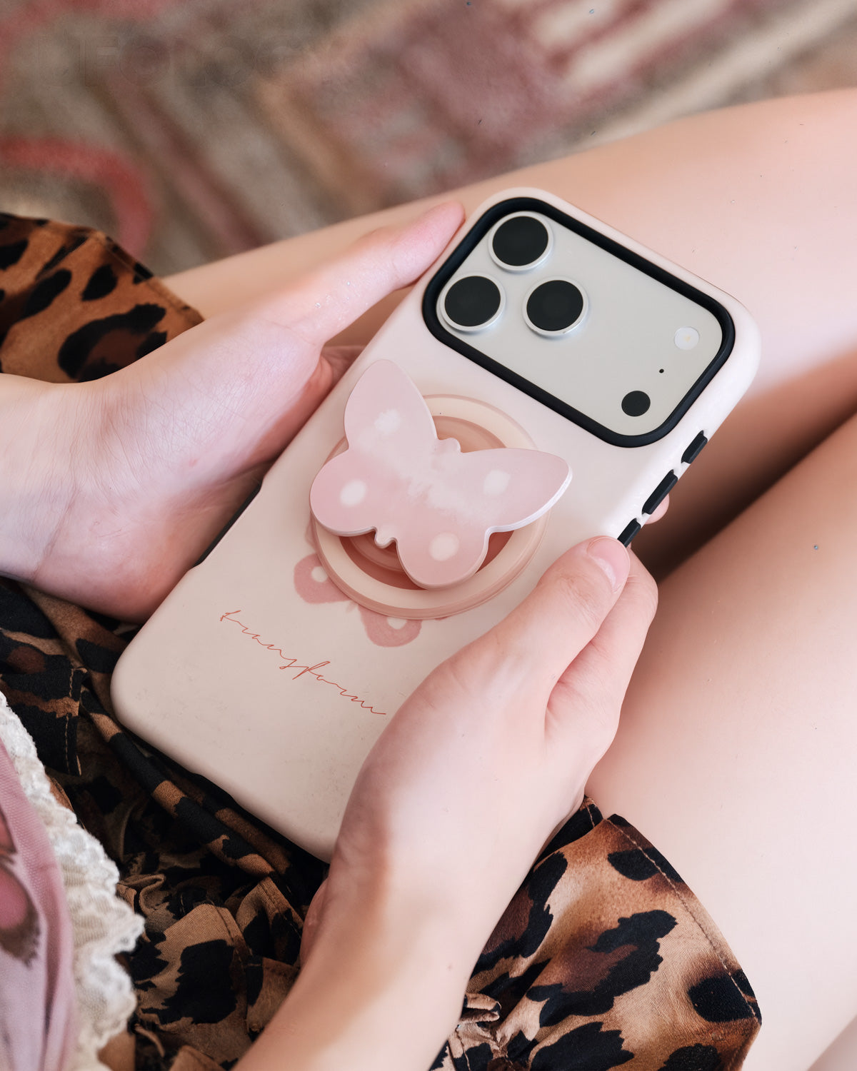 STICKYZOO pearl butterfly phone case held in hand with the retractable MagSafe grip extended