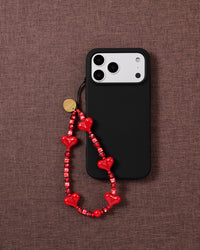 Cherry red heart bead phone strap worn hands-free from the wrist