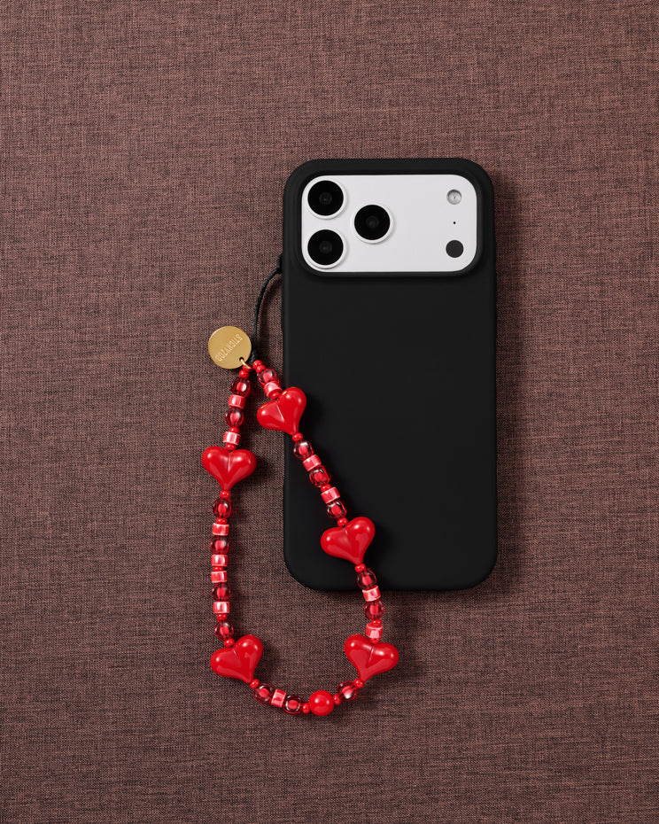 Cherry red heart bead phone strap worn hands-free from the wrist