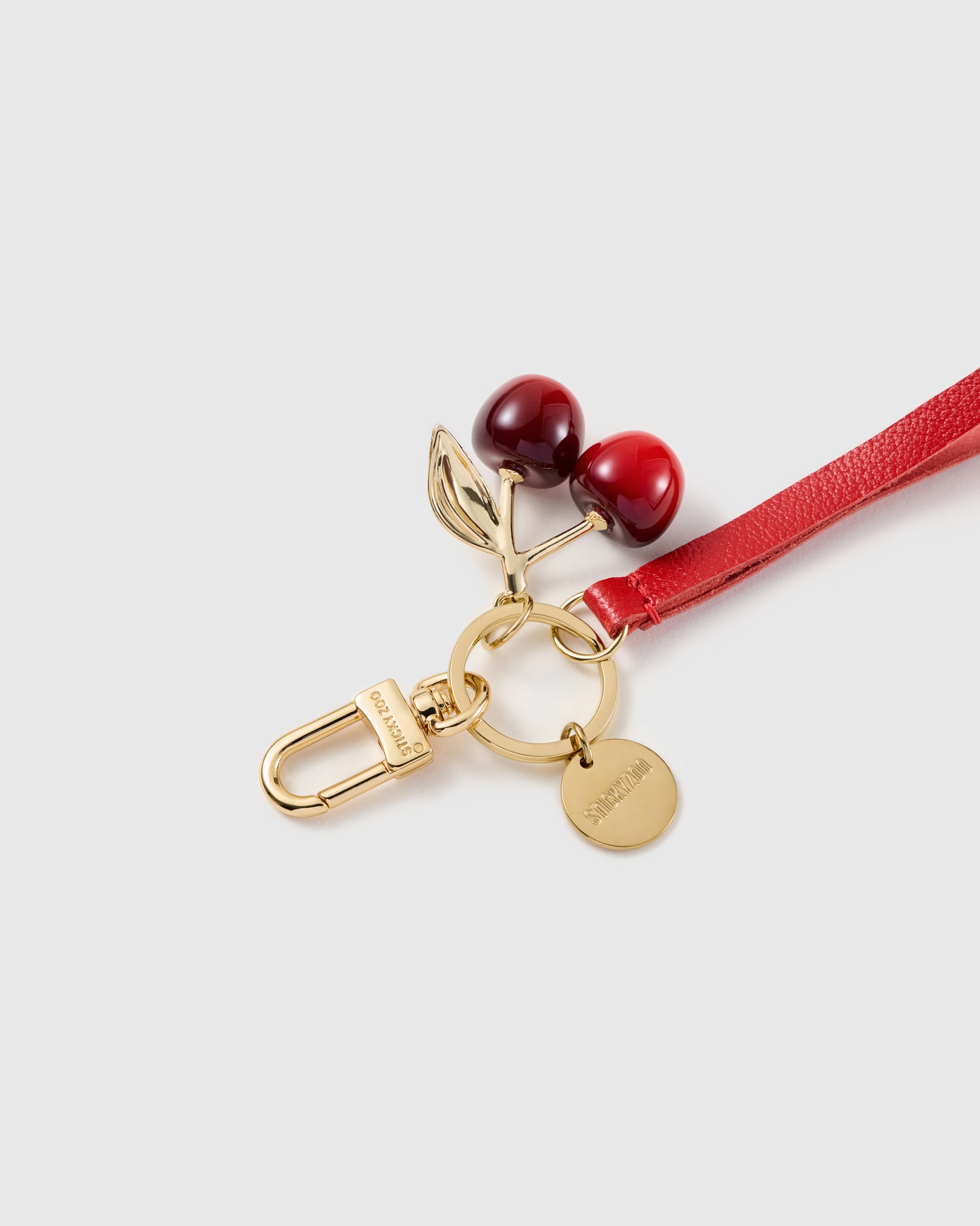 Crimson cherry leather phone strap clipped to a phone case showing the hands-free wrist loop in use