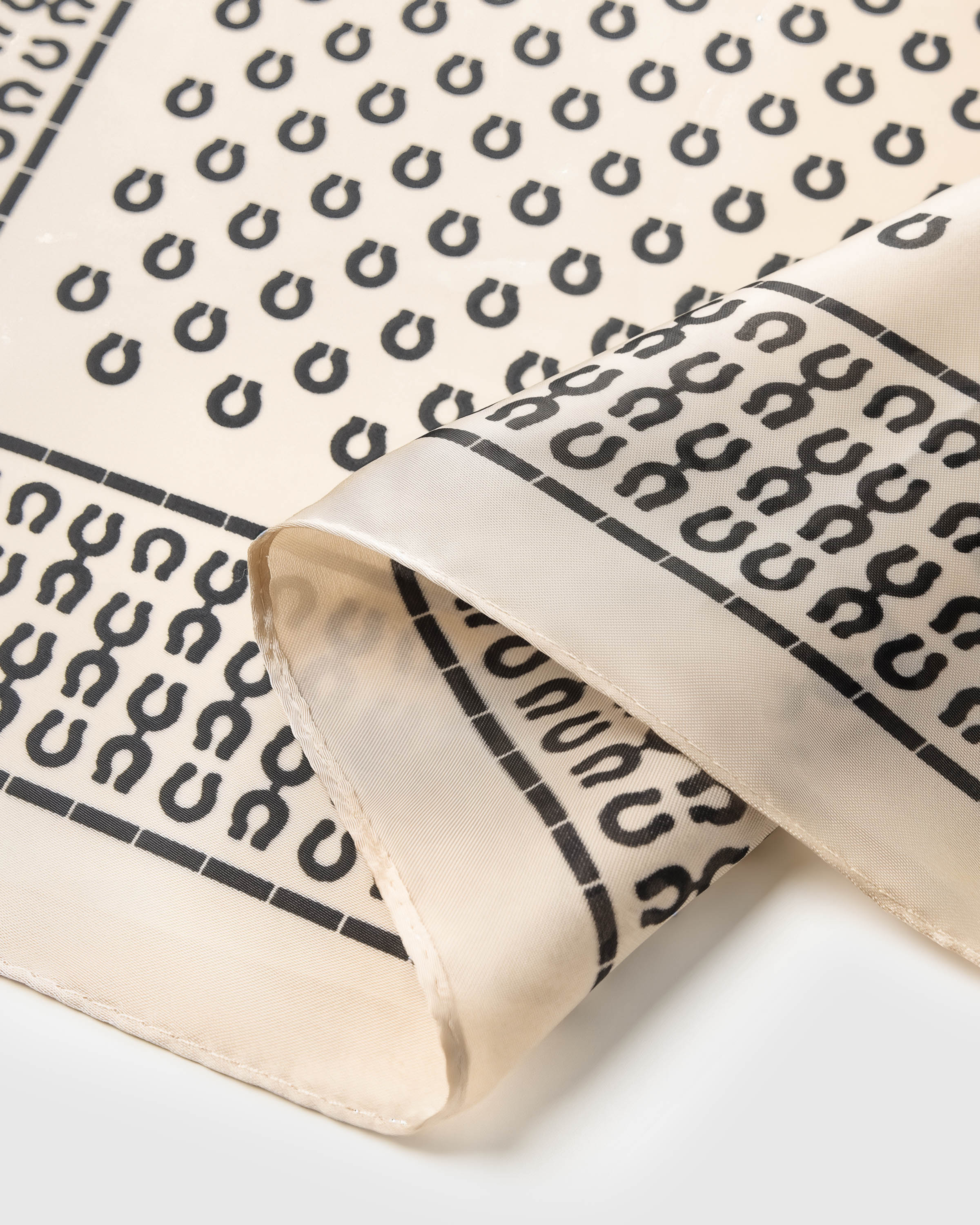 Close-up of the hand-illustrated horseshoe motif in charcoal archival ink on pure silk