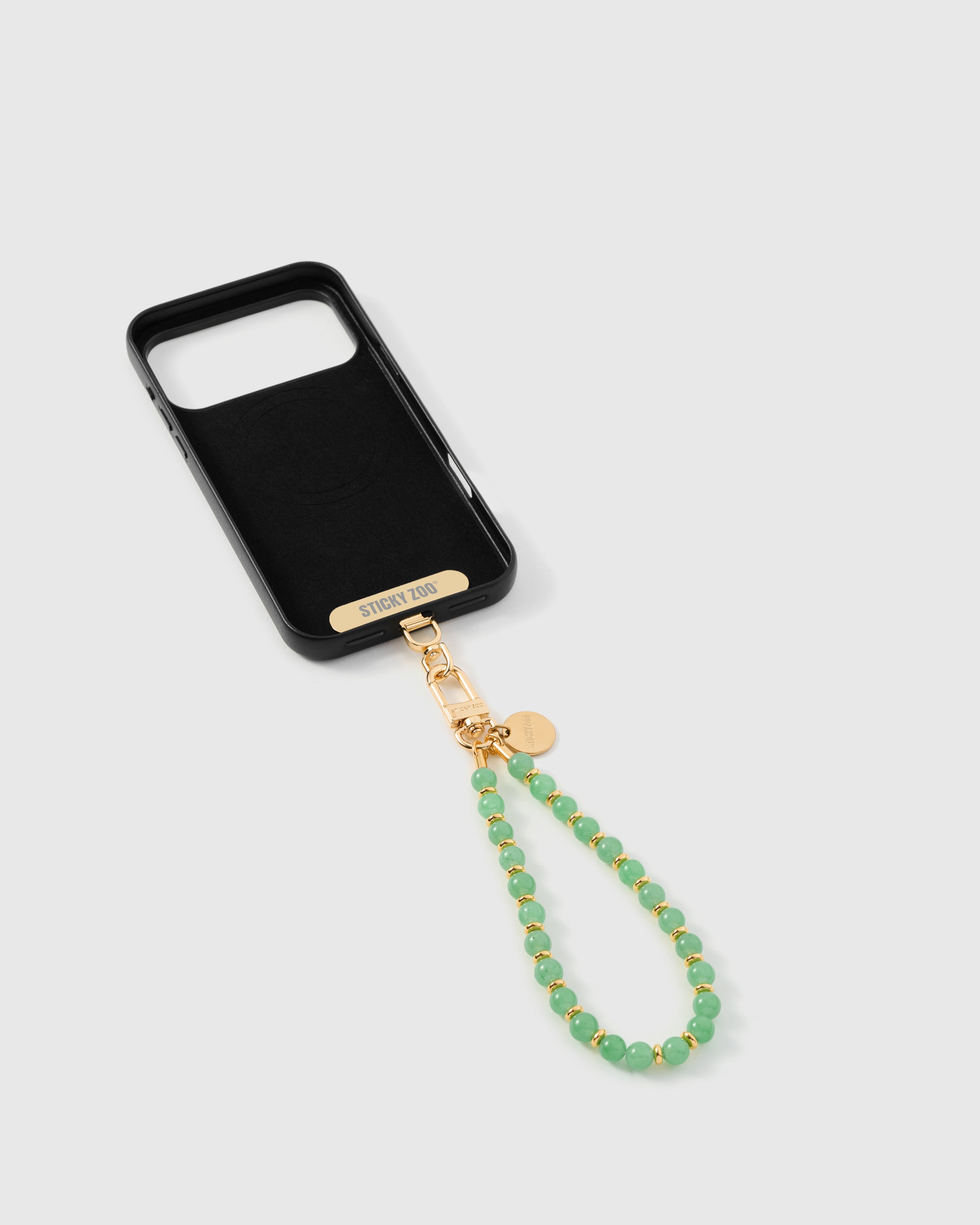 Inside of phone case showing STICKYZOO Phone Strap Card with sage orbit strap attached