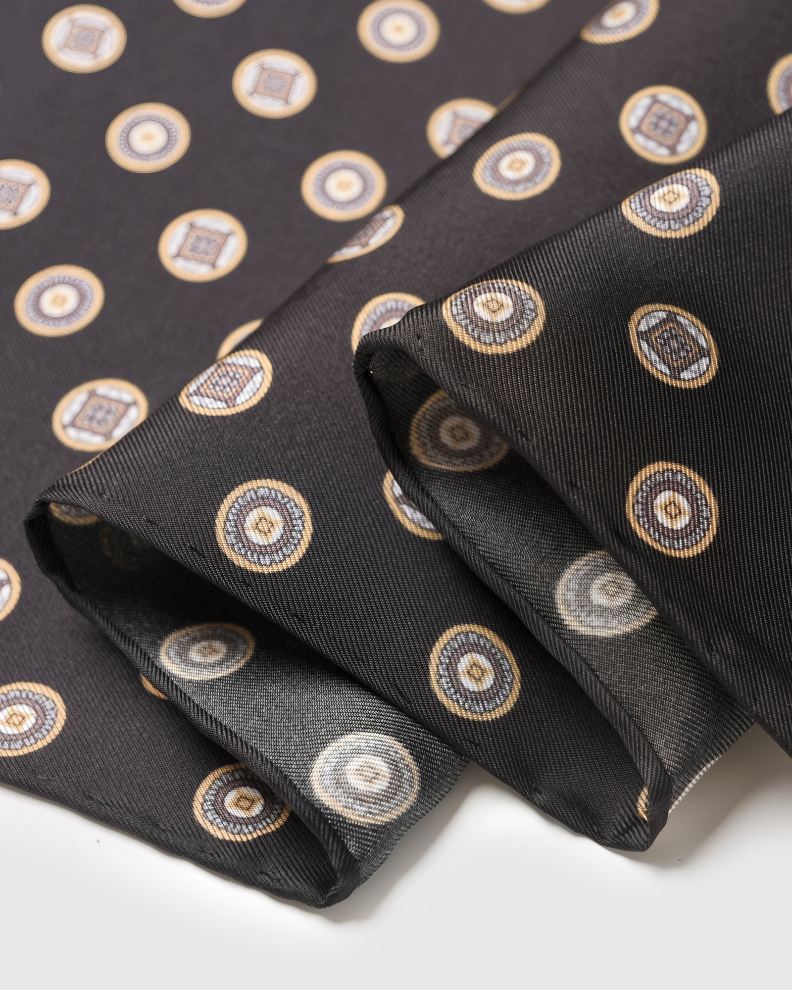 Close-up of the hand-illustrated coin medallions printed in archival inks on pure black silk
```