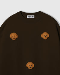 Close-up of plush poodle face applique on dark brown cotton showing golden curly fur texture
