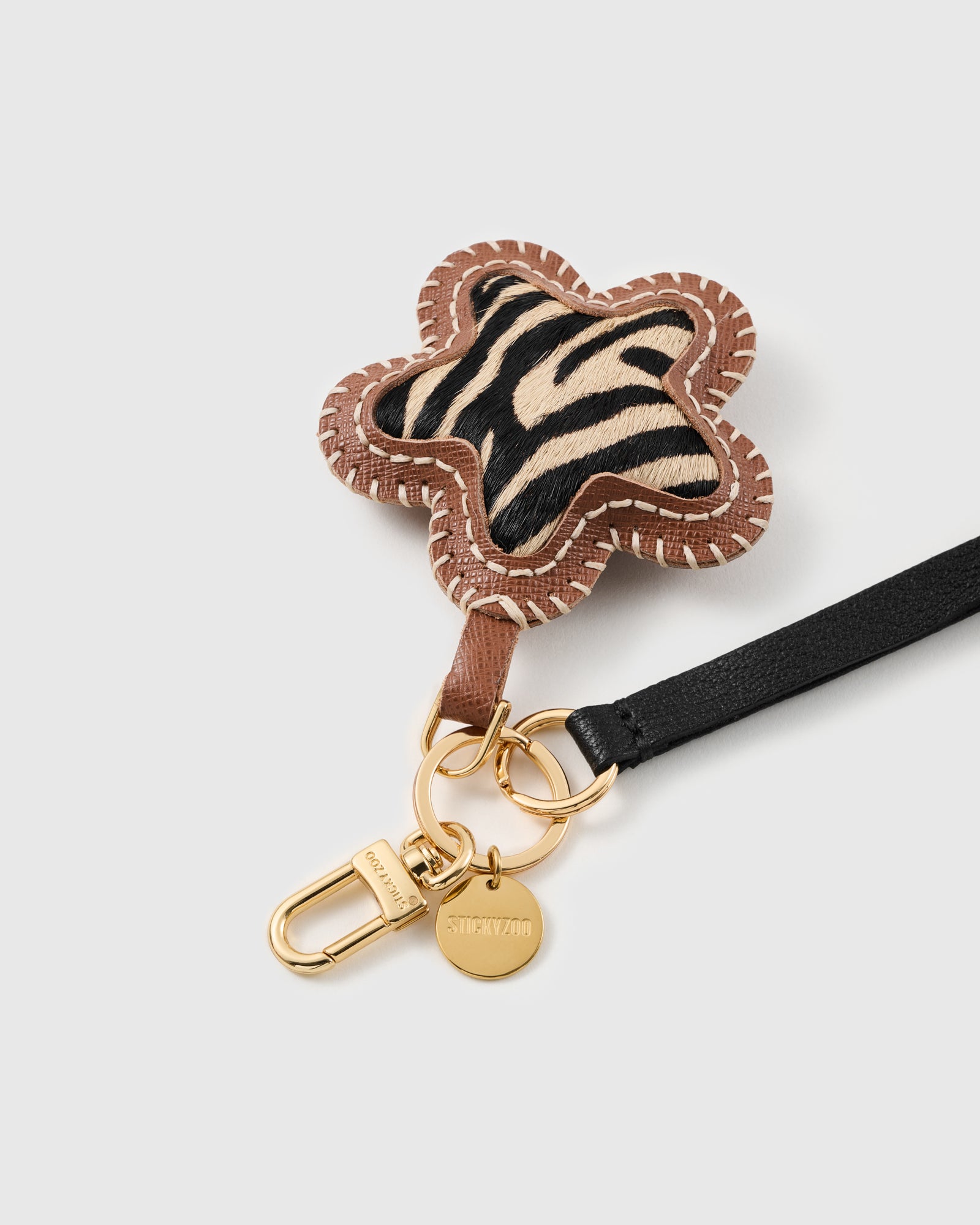 Close-up of the zebra calf-hair flower charm, hand whip-stitched leather frame and engraved STICKYZOO hardware