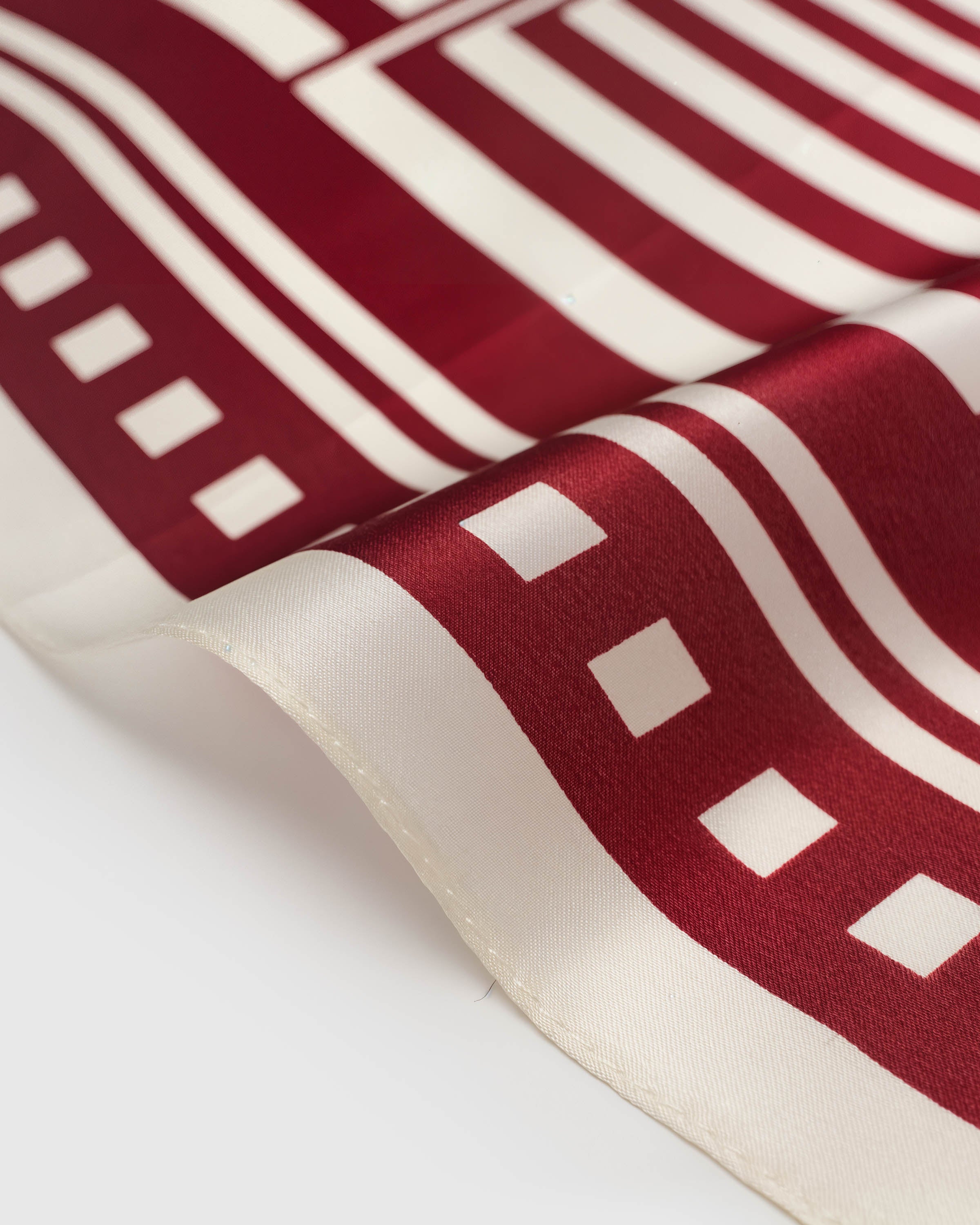 Close-up of the archival ink print on pure silk showing the crimson stripes meeting the ivory checkered border