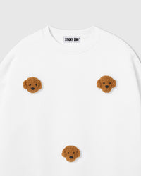 Close-up of hand-stitched plush poodle face applique showing curly golden fur and embroidered eyes on white cotton