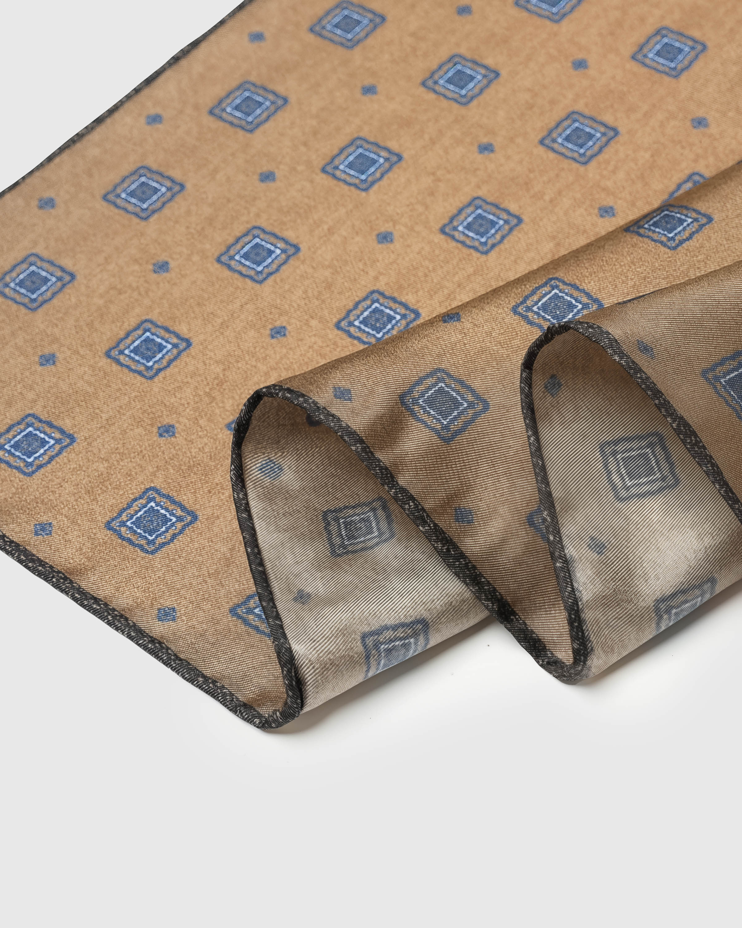 Close-up of the hand-illustrated blue diamond medallions printed in archival ink on warm camel silk