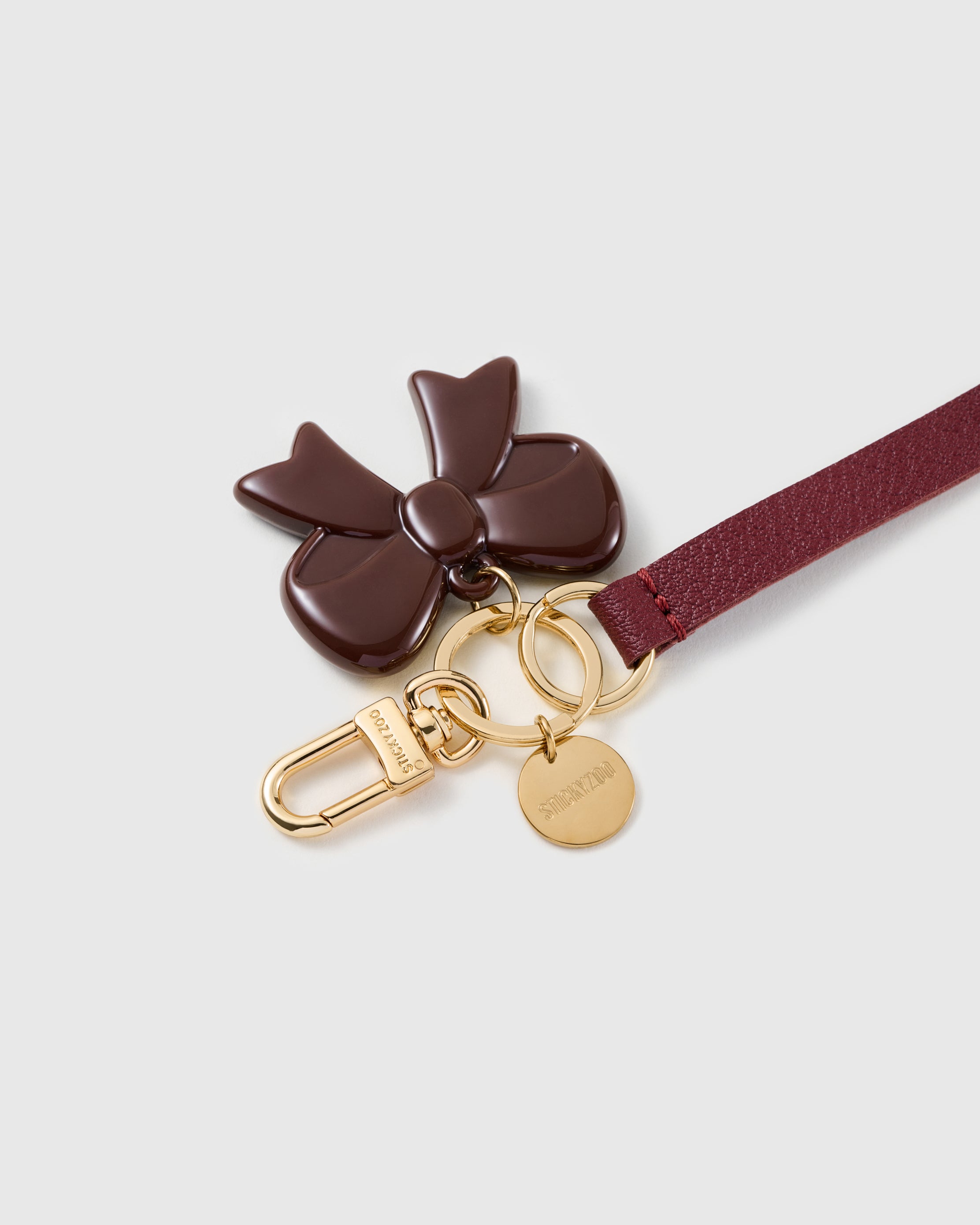 Cocoa bow leather phone strap clipped to a phone case showing the hands-free wrist loop in use