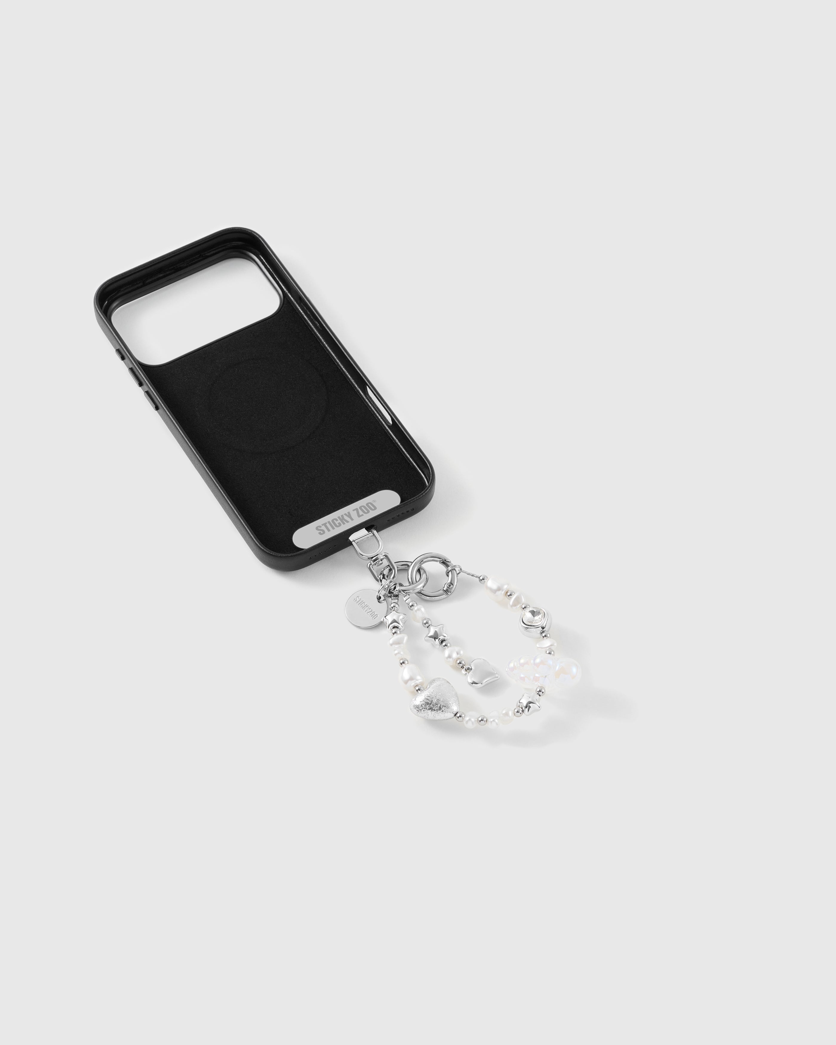 Beaded wrist strap on the back of a black MagSafe phone case, white pearl-effect beads, silver foil heart and iridescent cloud bead