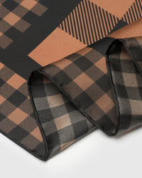 Close-up of the cognac and black gingham print on pure silk where the finer border meets the larger central check
