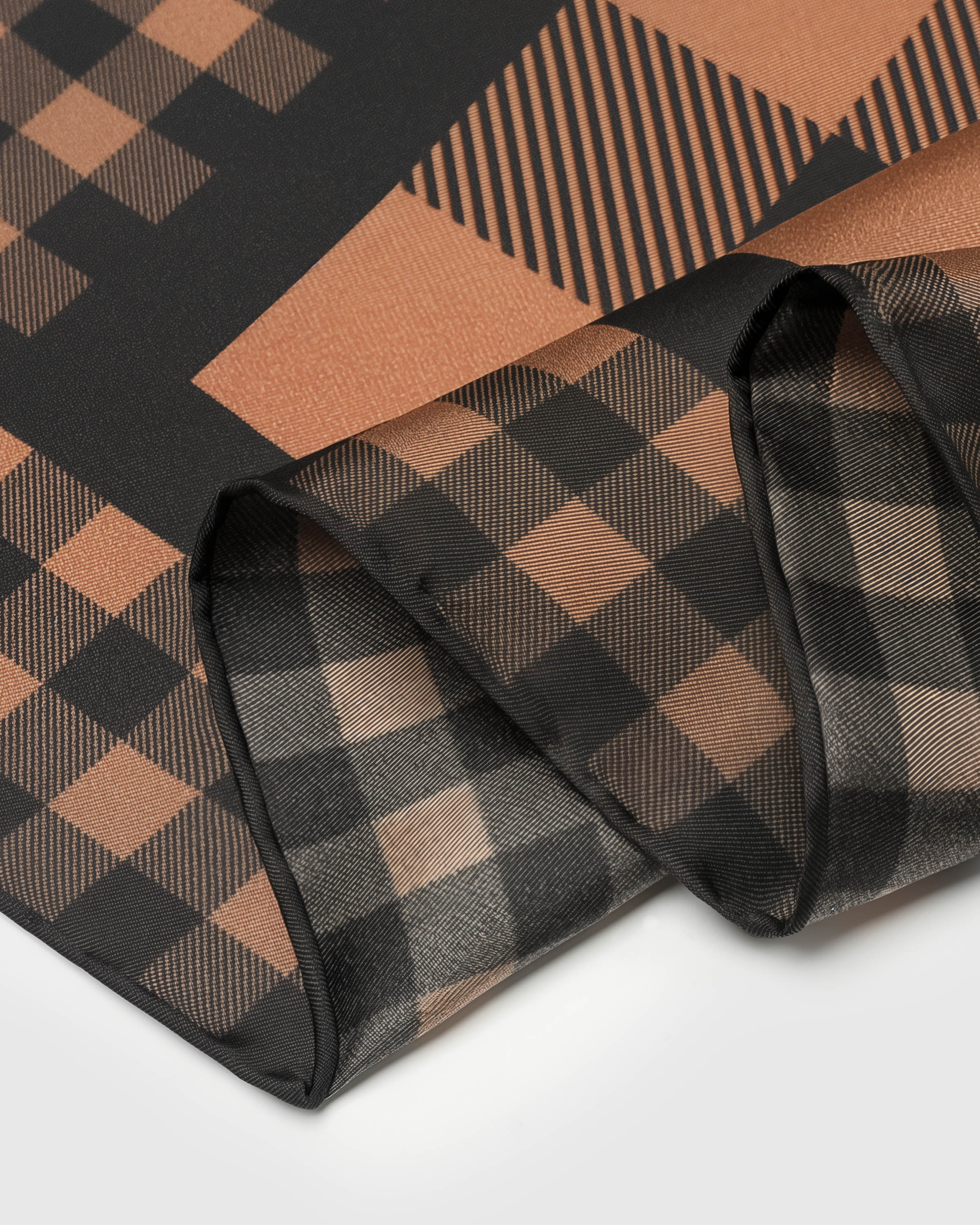 Close-up of the cognac and black gingham print on pure silk where the finer border meets the larger central check