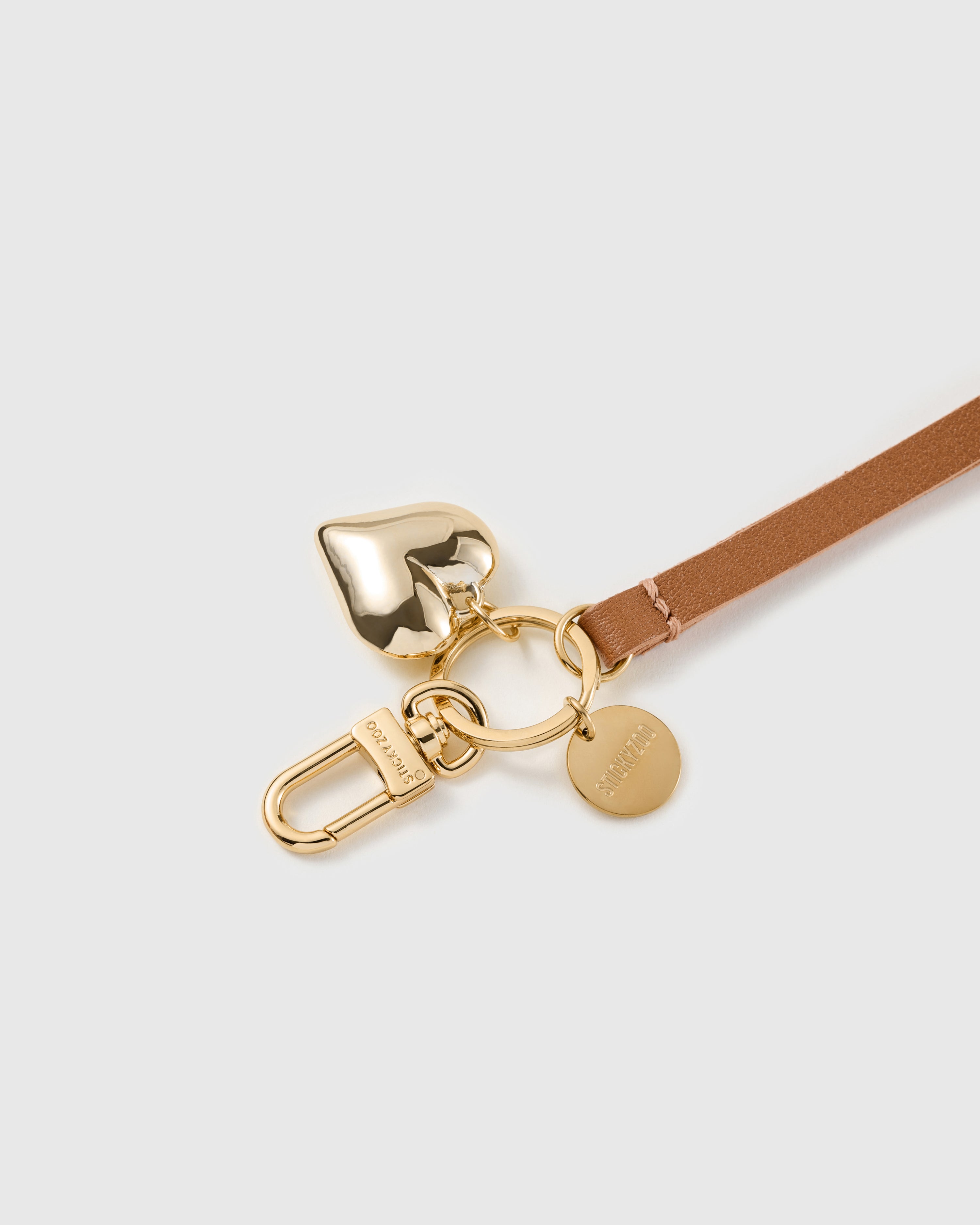 Golden heart leather phone strap clipped to a phone case showing the hands-free wrist loop in use