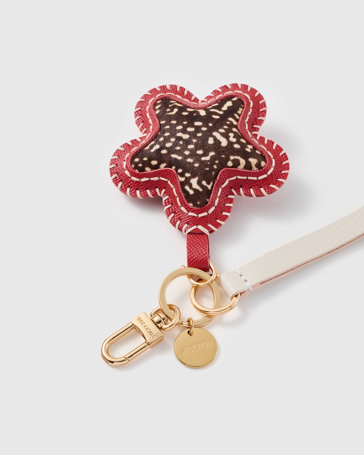 Close-up of the ocelot calf-hair star, hand whip-stitched red edge and engraved STICKYZOO disc