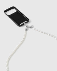 Silver-tone dual clasp linking the faux-pearl and heart strap to a black phone case, pearls trailing across a white studio backdrop.
