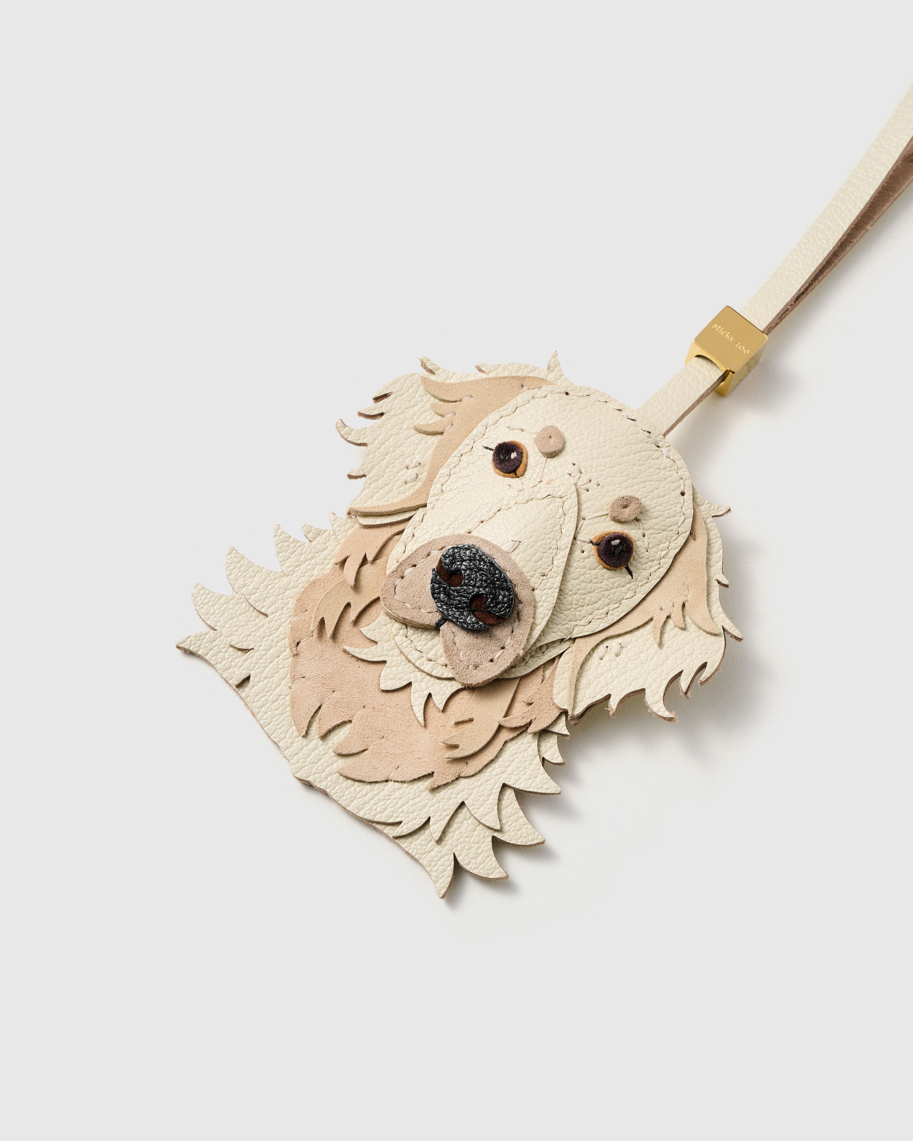 {{Hand-cut. Hand-stitched.}} Close-up of the Golden Retriever face, angled — layered muzzle, stitched lip lines, alcantara suede ears, textured dark nose. Every panel by hand.