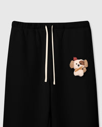 Close-up of plush puppy applique on black cotton sweatpant showing 3D stuffed texture and red beret detail