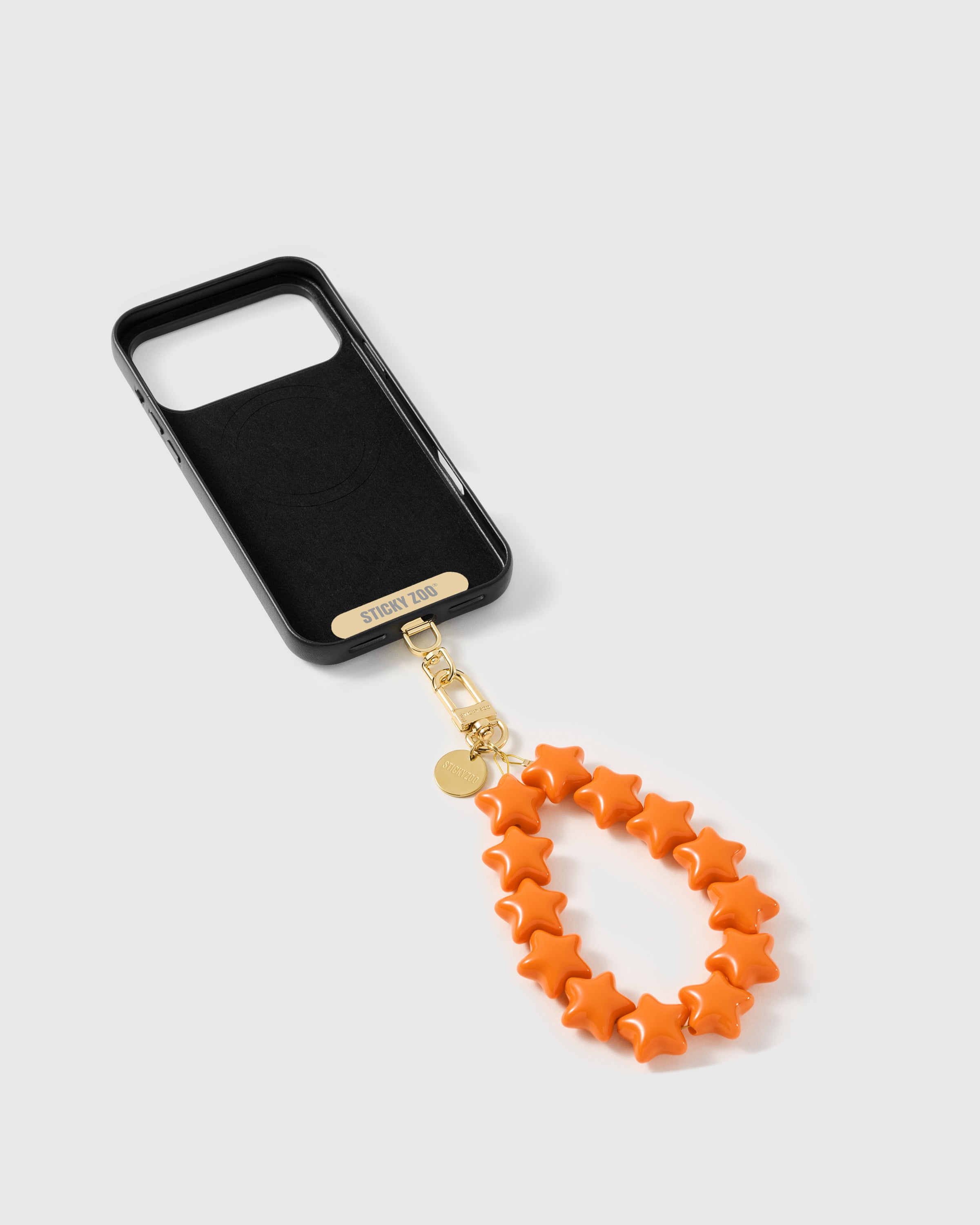 Back of an opened phone case showing the STICKYZOO Phone Strap Card slotted in — universal compatibility. 5,000+ Reviews.
