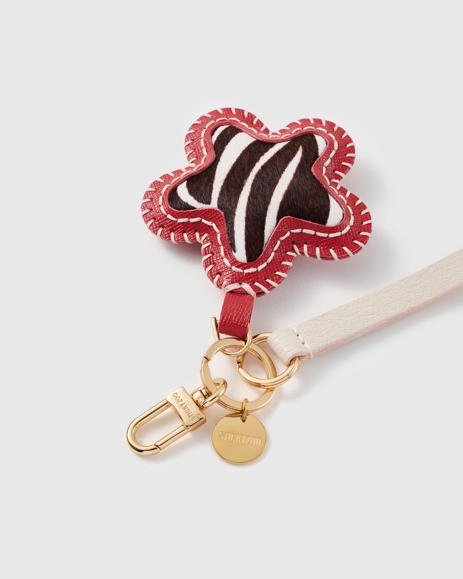 Close-up of the zebra calf-hair star, hand whip-stitched crimson edge and STICKYZOO gold disc