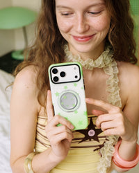Green star phone case held in daylight with the MagSafe pop-grip folded flat against the back for easy everyday carry.