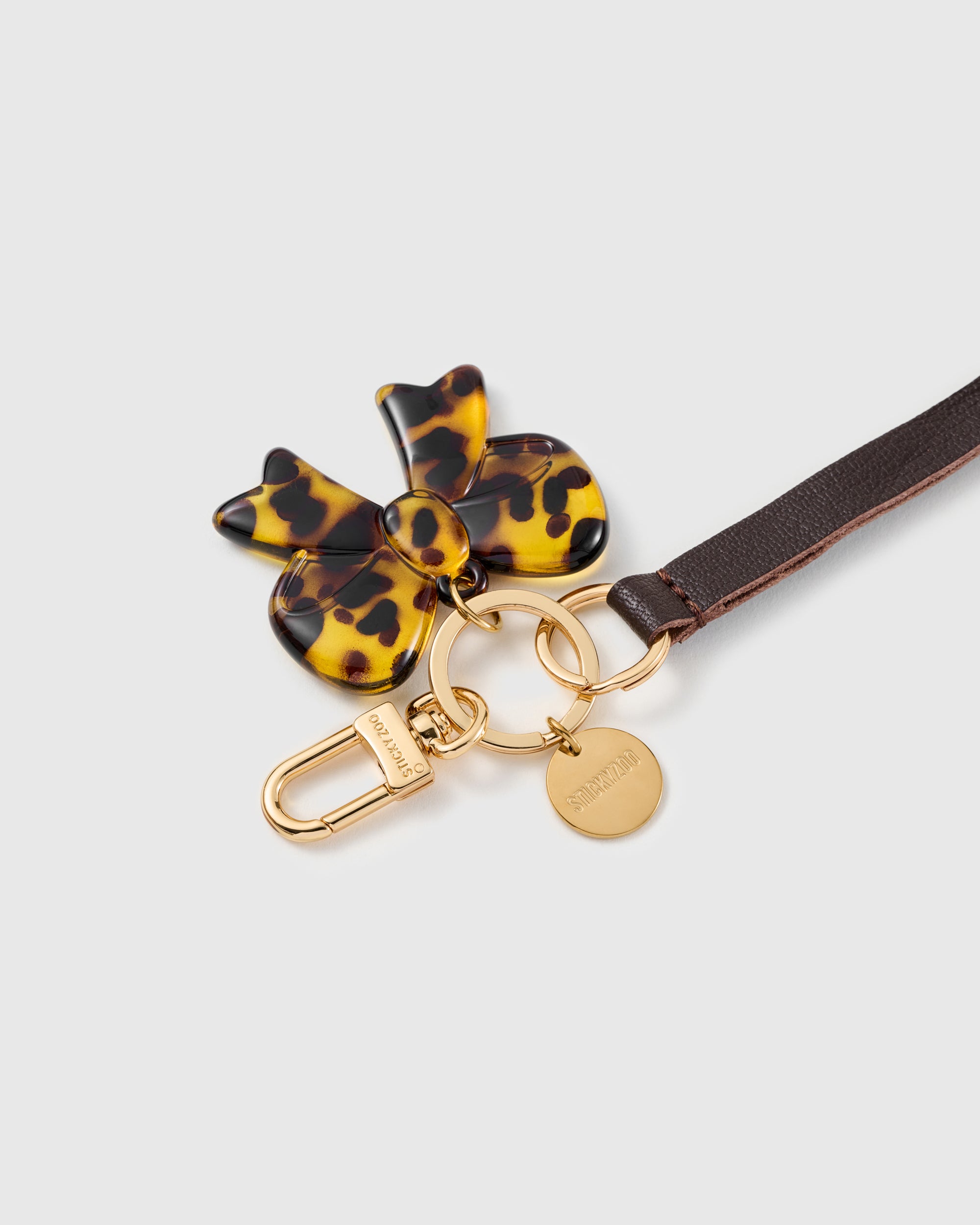 Tortoise bow leather phone strap clipped to a phone case showing the hands-free wrist loop in use