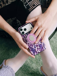 Hand holding the violet leopard phone case with fingers around the retractable MagSafe pop-grip